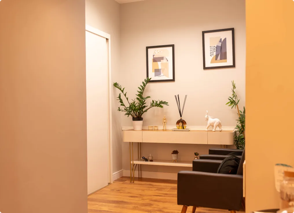 Espaço de espera com poltronas, plantas e quadros.
